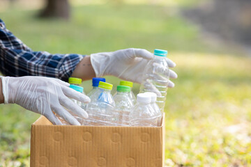 Close-up of a young volunteer collecting plastic bottles into a bin for recycling. The concept of...