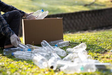 Close-up of a young volunteer collecting plastic bottles into a bin for recycling. The concept of...