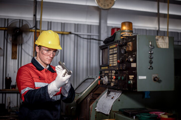 Engineer or factory worker wearing safety uniform under checking a metal part of lathe produce is quality control of parts machined on lathe structure Manufacturing industrial.