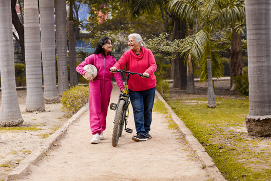 India Latin Grandmother and Grand daughter coming with cycle and Football in Garden, Retired life