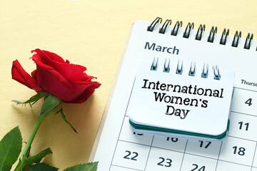 INTERNATIONAL WOMEN'S DAY. Women's day words in a notebook on a calendar next to a rose flower.