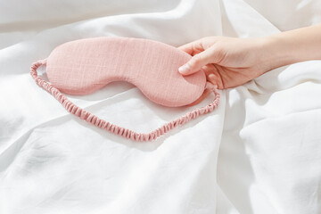 Pink eye mask for sleep on bed background, minimal lifestyle aesthetic, copy space. Top view woman...