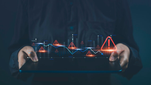 Business economy crisis and investment risks. Tablet show virtual stock graph data fall with alert warning sign for caution finance investing economic recession situation warning.