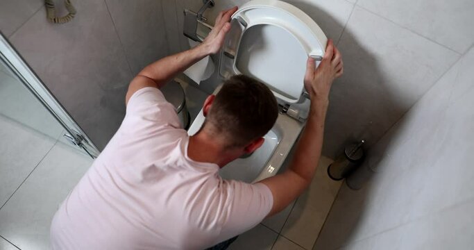 Man opening toilet lid and vomiting at home 4k movie slow motion. Nausea and vomiting as symptom of gastroenteritis concept