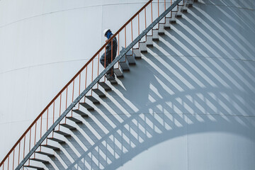 A male walking the upstairs inspection visual record storage tank oil stairs