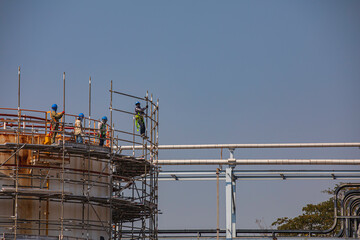 Construction workers installing scaffolding storage tank Oil​ refinery​ and​ plant and tower column