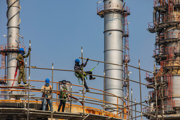 Construction workers installing scaffolding storage tank Oil​ refinery​ and​ plant and tower column