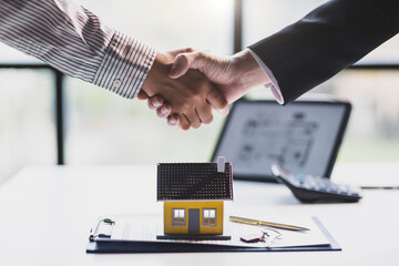 Businessman shaking hands with real estate agent in office after reaching home purchase agreement.