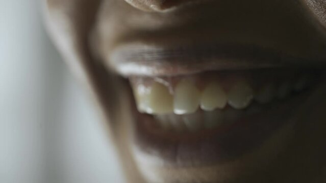 Macro shot of female model face. African American woman macro shot of eyes and mouth, model smiling showing white teeth, looks away from camera.