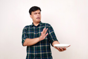 Portrait of young asian man showing rejection hand gesture with food on a plate