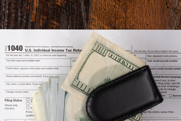 Individual tax return 1040 form payment concept with one hundred dollar bills.  Tax day or tax deadline.