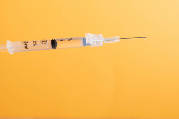 Medical syringe and needle with fluid dripping out of needle.