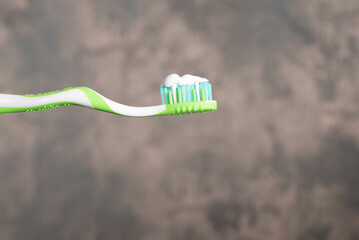 Green and white toothbrush with white toothpaste. Dental health awareness concept.