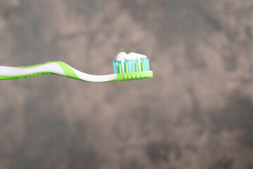Green and white toothbrush with white toothpaste.  Dental health awareness concept.
