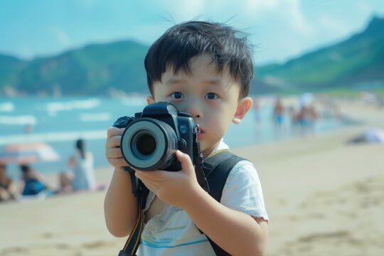 The handsome Chinese boy is on the sunny beach, carrying a heavy camera and taking pictures of the beautiful scenery,