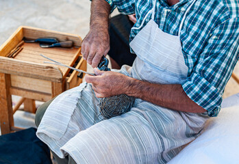 Craftsman is building a wicker basket during a fair of old crafts
