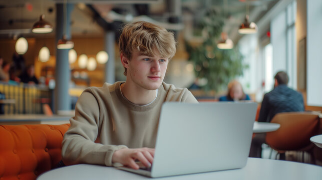 Young man working on laptop, IT programmer freelancer or student with computer in cafe at table looking in camera