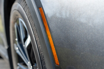 Front fender of a modern car with reflector in focus and tire in the background