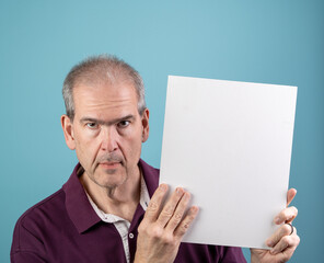 Sixty-year-old man holds up a blank white sign with room for copy and points to it