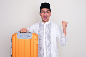 Moslem Asian man carrying suitcase with excited expression