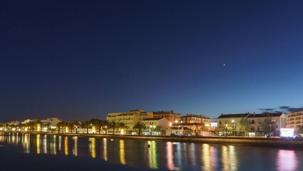 Bensafrim River at night with reflection of light from the houses at the N125 in the town with planet Venus on the sky, Lagos, Algarve, Portugal