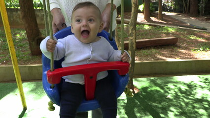 Happy baby at playground swing