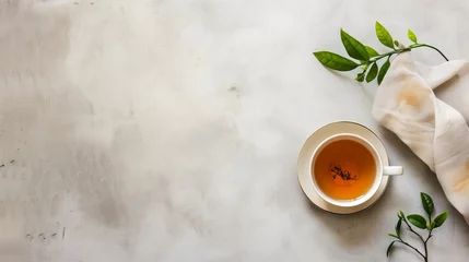 Deurstickers a cup of tea and green tea leave on minimalistic studio background, free copy space © Aliaksandra