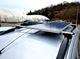 traveler has a solar panel on the roof racks on the roof of the small camper van. Very simply, he can use the sun to charge the batteries and light the inside of the car, home made