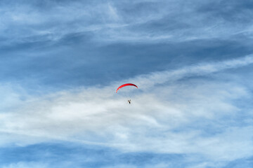 A paraglider soars in the vast blue sky, embodying freedom and adventure. This image can be a...