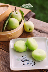 A plate of green apples and a basket of apples on a wooden table. Mochi asian dessert