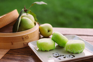 A plate of green apples and a basket of apples on a table. Mochi asian dessert