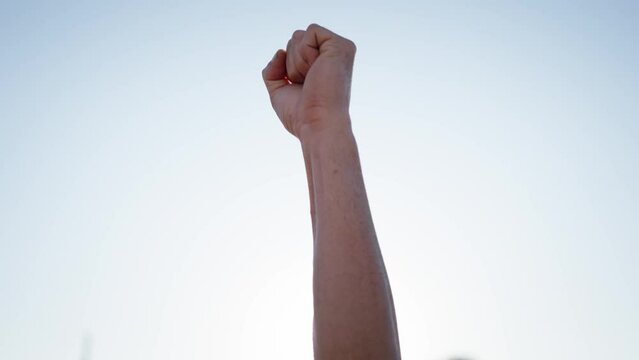 Hands unrecognizable person raising arms cheering or celebrating victory. Shot of cropped man clenched fists as he celebrates success on blue sky and lens flare background. Copy space fit male people