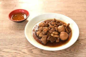 braised pork and meatball in herb brown soup on dish and spicy chili sauce 