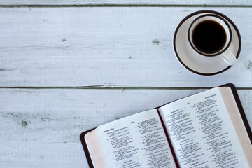 Open holy bible book with coffee cup on wooden background. Top view. Copy space. Studying and...