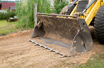 Large wide bucket with metal teeth of heavy front loader or bulldozer close-up. Copy space. Transportation and movement of bulk materials. Excavator shovel. Attachments