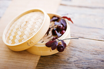 a bamboo steamer filled with grapes on a wooden table