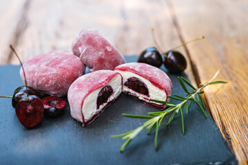 a close up of a dessert with cherries and rosemary on a table. Mochi asian dessert