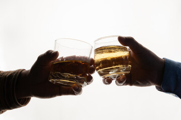 Two men's hands clinking whiskey glasses against a white background. bar drink menu