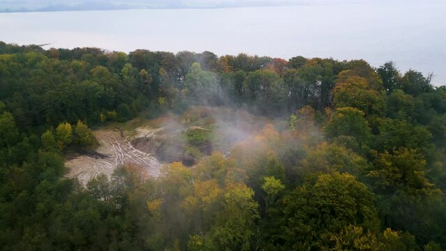 Herbstlicher Wald mit Rodungsfl&auml;che und Nebelschwaden nahe einem ruhigen See im Morgengrauen. Drohnenaufnahme. Ziegelei Fisken&aelig;svej, Graasten, D&auml;nemark