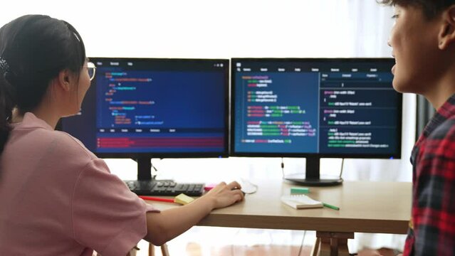 Slow motion back end software developer engineer for computer programming working together on debugging writing computing code, solving complex algorithms display on monitor in office. Burgeoning