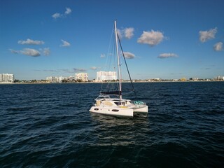 A catamaran sailboat anchored at sea on a calm ocean just off the coast of South Florida