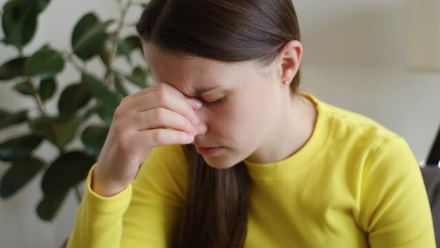 Close up of upset sad young caucasian woman has dizziness and motion blurry sitting alone on couch in living room at home. Brain stroke or low blood pressure symptom on people medical concept
