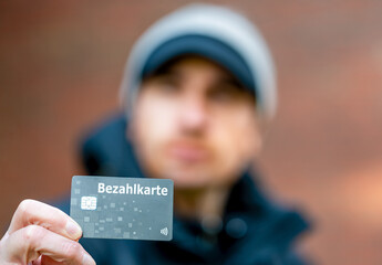 A refugee with a payment card (Bezahlkarte) in Germany. Symbol for the new payment card for refugees in Germany. - obrazy, fototapety, plakaty