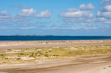 Amrum Strandansicht vom Strand von Norddorf mit Strandkörben am Horizont die Nachbarinsel Sylt mit dem Leuchtturm von Hörnum