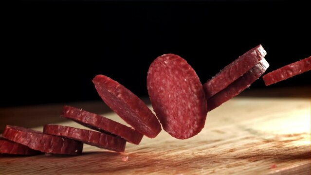 Pieces of salami fall onto a wooden board. Filmed on a high-speed camera at 1000 fps. High quality FullHD footage