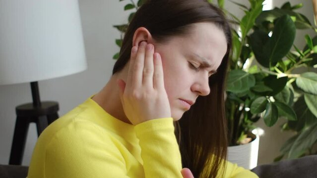 Close up of sick young woman have ear pain or earache, hand touch plug ear, suffering painful otitis from loud or noisy sound, inflammation. Health care nerve deaf eardrum disease. Tinnitus concept
