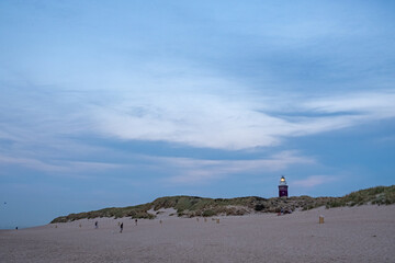 This image captures the essence of a tranquil evening on a sandy beach as dusk descends. A few...