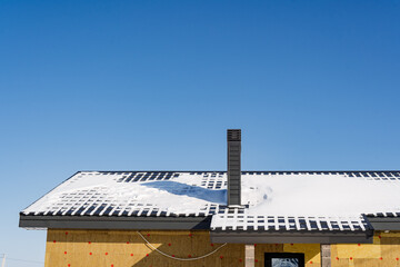Snowcovered roof on a house in the process of construction under the clear sky