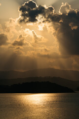 Dramatic Sunset with Sunbeams over Sea and Silhouetted Mountains