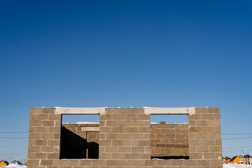 Building under construction with brickwork facade against blue sky